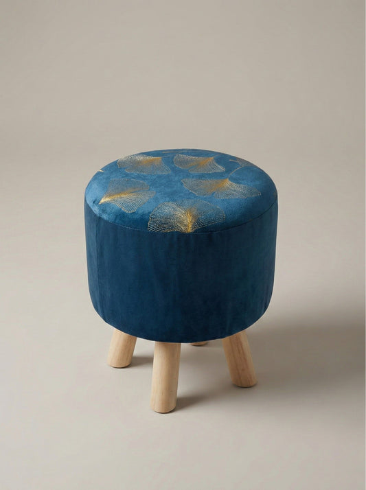 Puff azul acolchado con patas de madera, vista frontal en fondo neutro