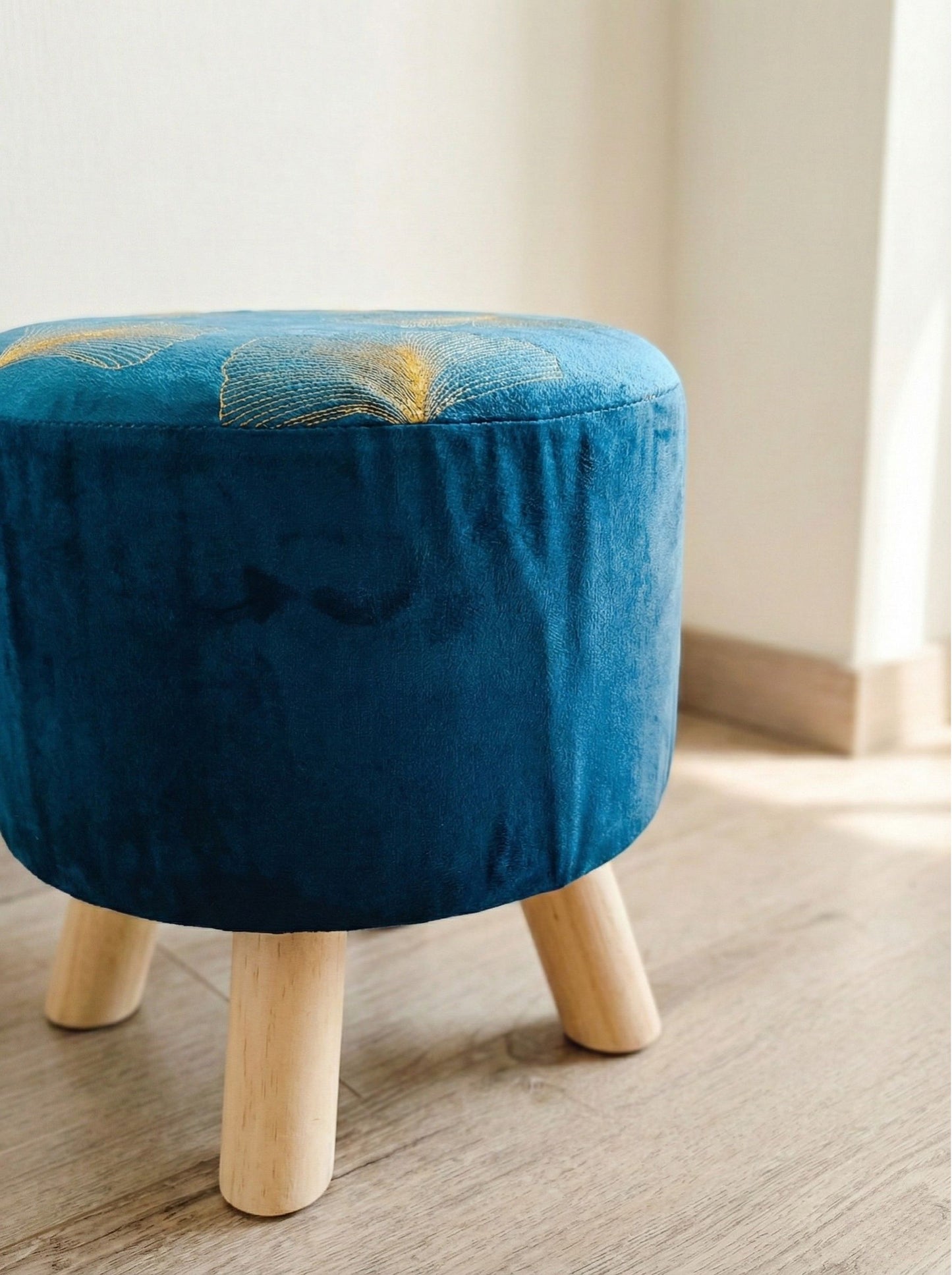 Puff azul acolchado vista lateral, patas de madera natural
