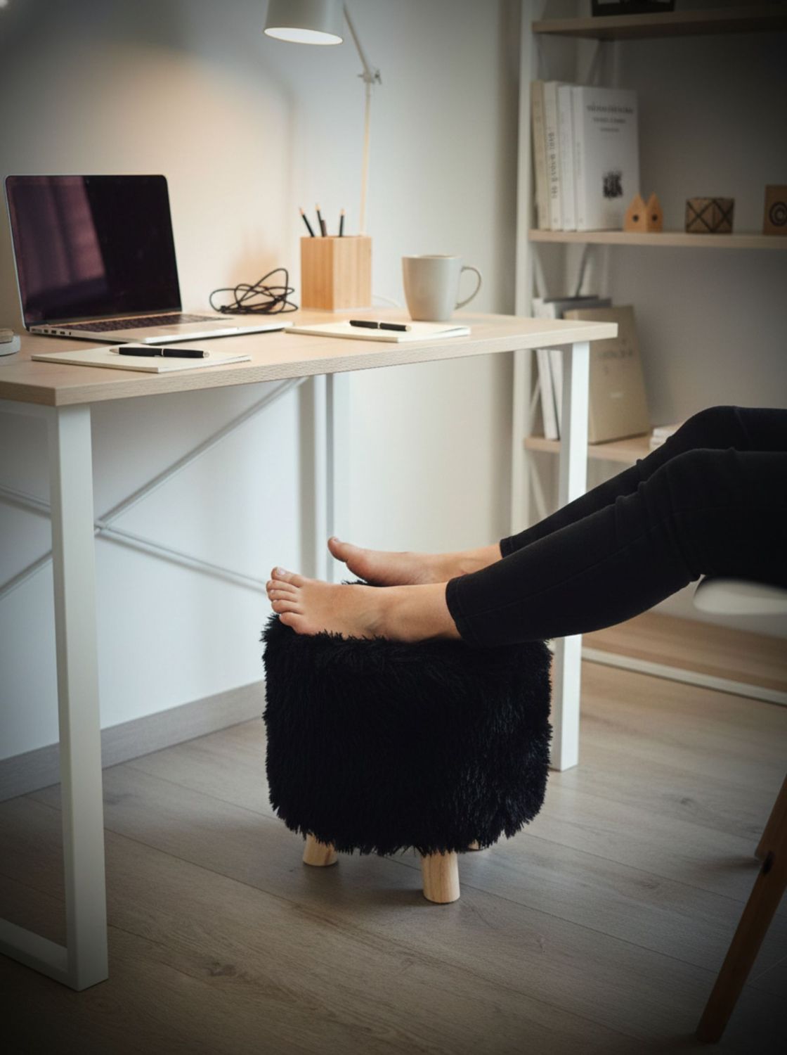 Puff negro peludo como apoya pies bajo escritorio en home office